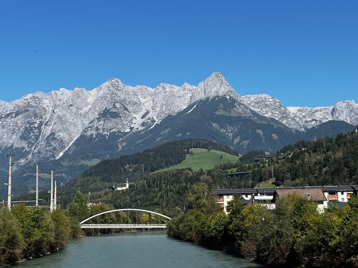 Blick von einer Brücke auf einen milchig grünen Fluss zwischen bewaldeten Hängen