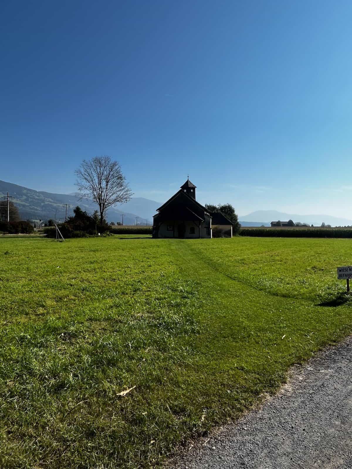 Weite grüne Wiese mit kleiner Kapelle vor alpinem Panorama bei Spittal