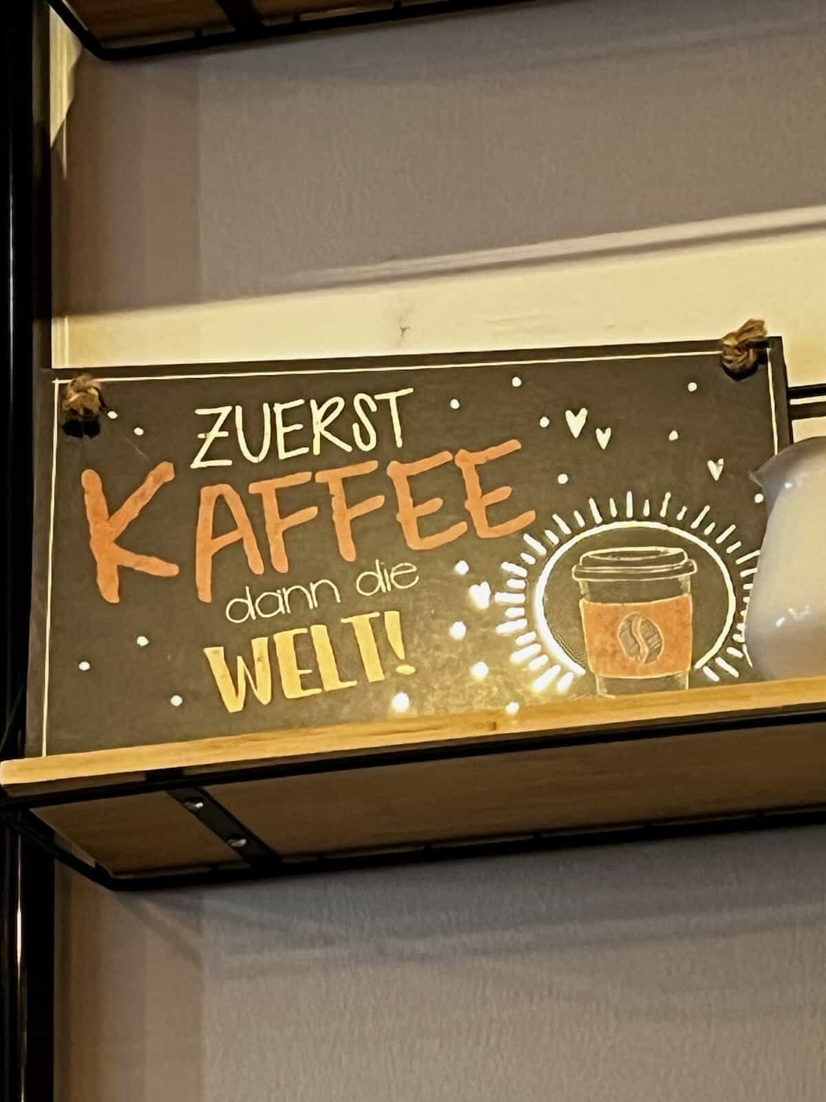 Handgeschriebenes Caféschild mit der Aufschrift „Zuerst Kaffee, dann die Welt“