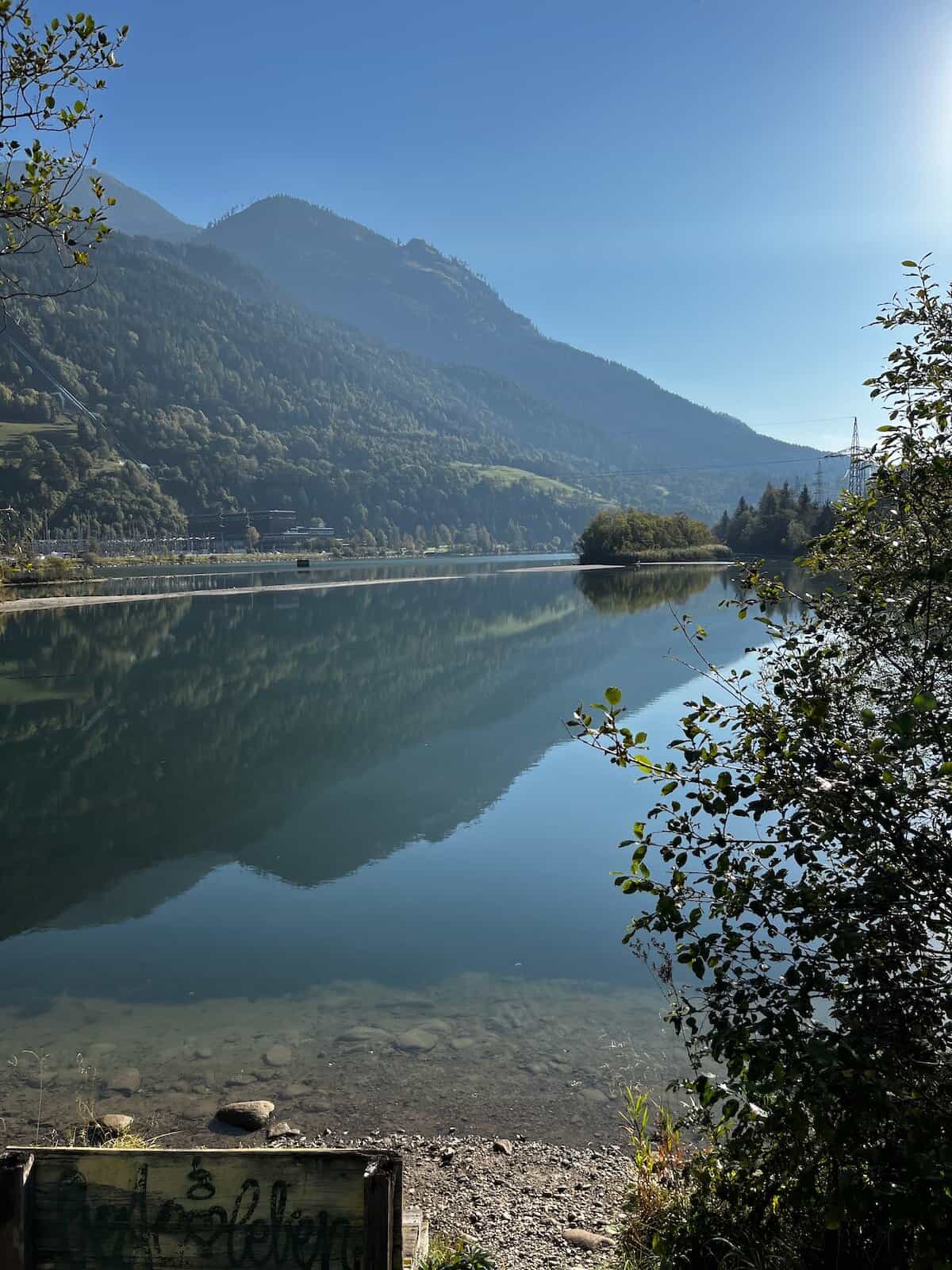 Klarer Gebirgsfluss mit Steinen und herbstlicher Vegetation