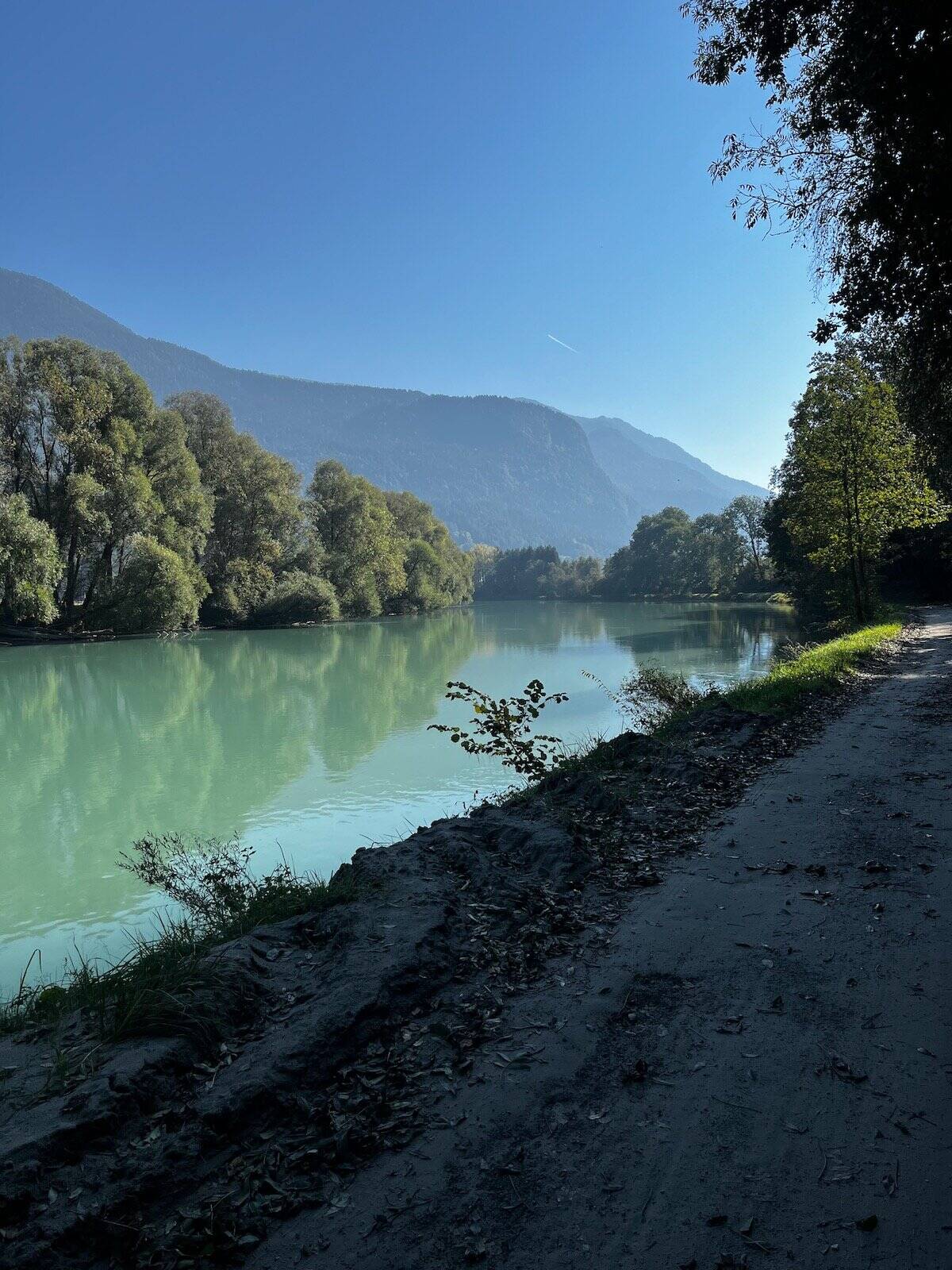 Schotterweg entlang der Drau mit Bergen im Hintergrund