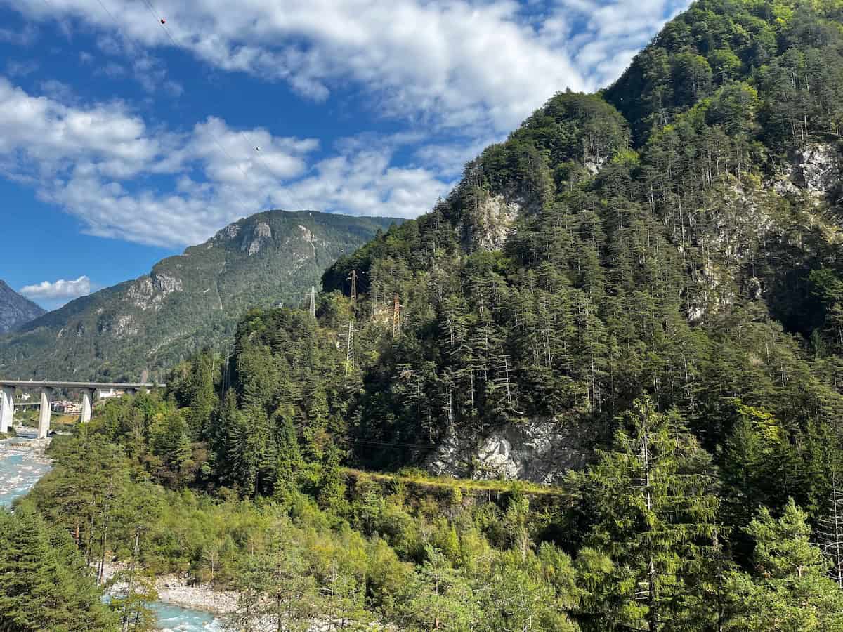 Steile grüne Berghänge unter blauem Himmel, landschaftliche Vielfalt der Alpe-Adria-Radreise