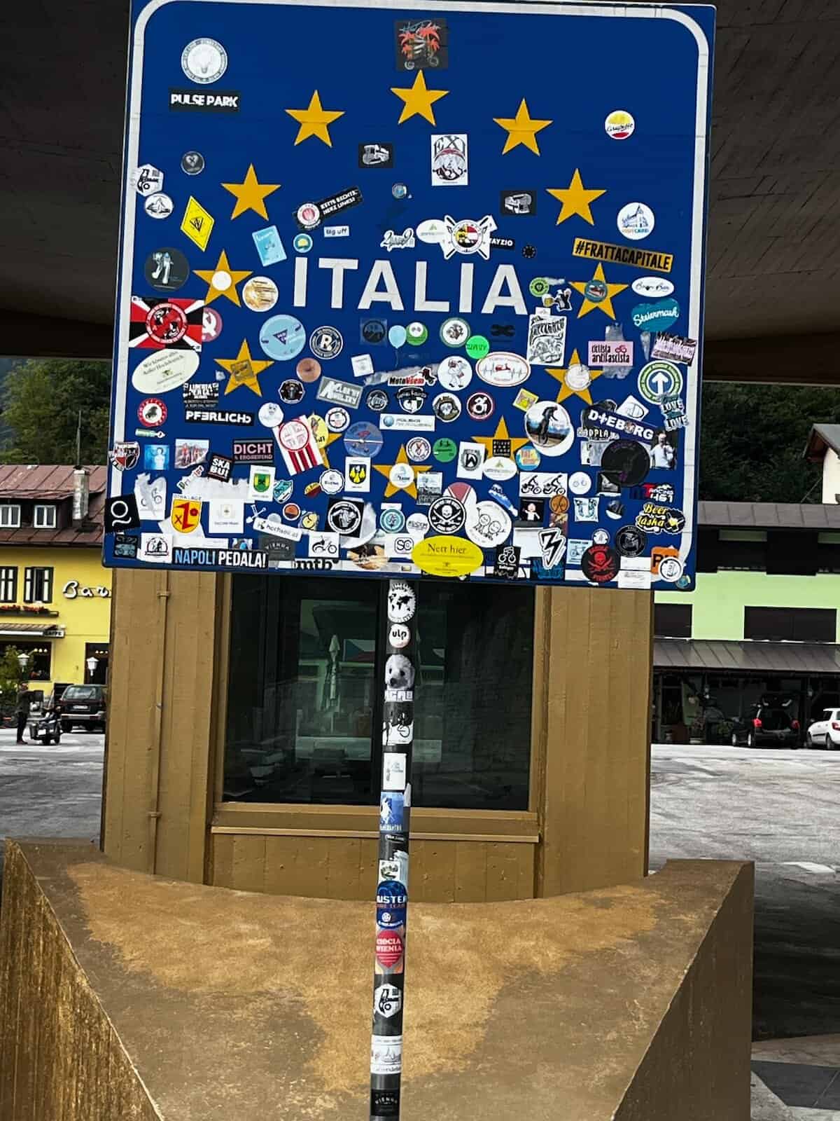 Stickerbeklebtes Ortsschild Italia als Symbol für Grenzüberquerung auf der Alpe-Adria-Radreise