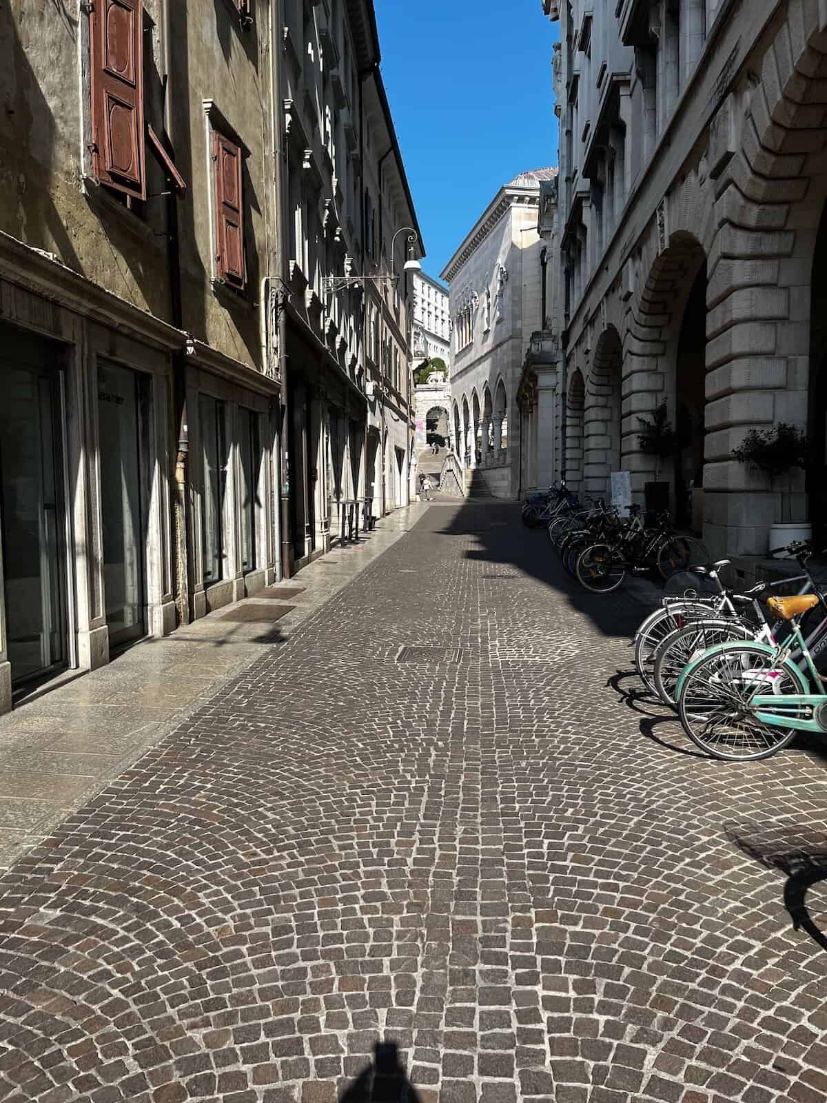 Kopfsteinpflasterstraße in Udine mit Fahrrädern, urbaner Abschnitt des Alpe Adria Radwegs