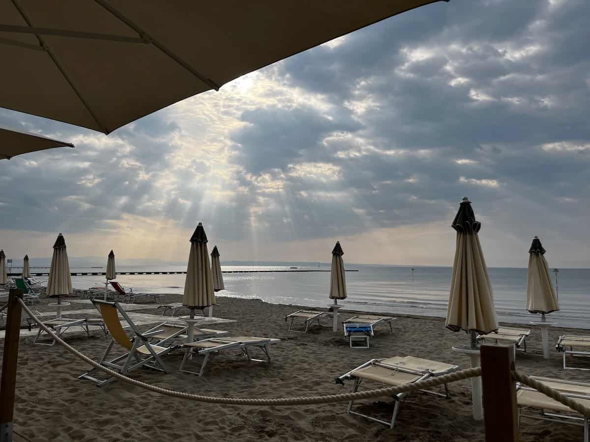 Strandliegen und Sonnenschirme in Grado bei ruhigem Meer, Erholung nach dem Alpe Adria Radweg